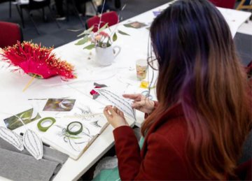 Image of artist creating with fresh flowers and twine on a table top